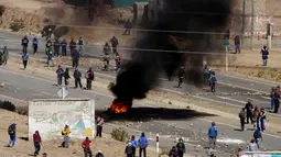 Penambang independen membakar ban saat aksi protes menuntut perubahan undang-undang di Panduro, sekitar 160 km dari ibukota Bolivia, Kamis (25/8). Aksi protes ini berubah menjadi kekerasan setelah mereka memblokade jalan raya. (REUTERS/David Mercado)