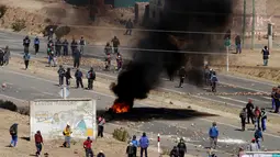 Penambang independen membakar ban saat aksi protes menuntut perubahan undang-undang di Panduro, sekitar 160 km dari ibukota Bolivia, Kamis (25/8). Aksi protes ini berubah menjadi kekerasan setelah mereka memblokade jalan raya. (REUTERS/David Mercado)