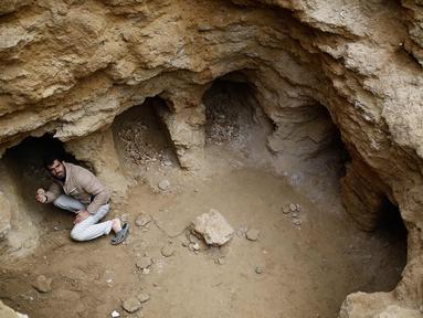 Abdel-Karim Cafran, warga Palestina Beit Hanun mengumpulkan pecahan tembikar di sebuah pemakaman yang baru ditemukan di kebun rumahnya di kota di Jalur Gaza utara, (26/1). (AFP Photo/Mohammed Abed)