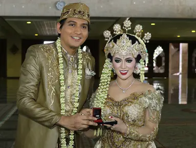 Lucky Hakim dan Tiara Dewi saat menunjukkan mahar dan cincin nikah seusai akad nikah di Masjid At Tin, Jakarta, Kamis (19/1/). Lucky Hakim dan Tiara Dewi melaksanakan akad nikah hari ini dengan mahar 500 gram logam mulia. (Liputan6.com/Herman Zakharia)