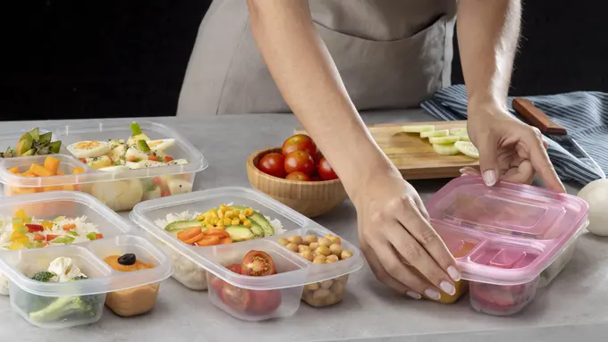Seorang perempuan sedang menyiapkan kotak bekal dengan makanan sehat (Foto Dok: Freepik/freepik)