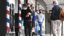 Para pria antre untuk memotong rambut di luar barber shop di Melbourne, Australia, Senin (19/10/2020). Warga Kota Melbourne, pada Senin (19/10), akhirnya bisa bernafas lega saat sejumlah pembatasan dilonggarkan setelah lockdown tahap keempat yang ketat selama sekitar 100 hari. (William WEST/AFP)