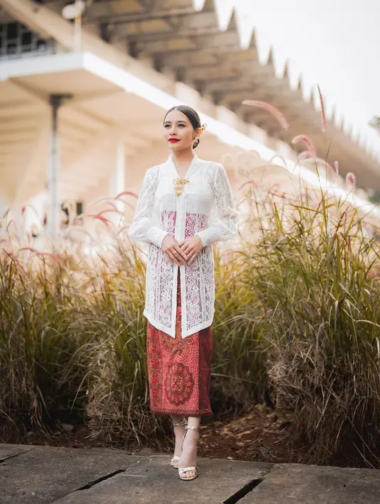 Prilly Latuconsina pakai kebaya Kartini berlengan balon dengan angkin merah dan rok kain. Prilly lengkapi kebayanya dengan bros tumpuk emas [@prillylatuconsina96]