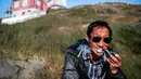 Seorang pria mengisap pipa di Desa Kulusuk, Kota Sermersooq, Greenland, Denmark, 21 Agustus 2019. (Jonathan NACKSTRAND/AFP)