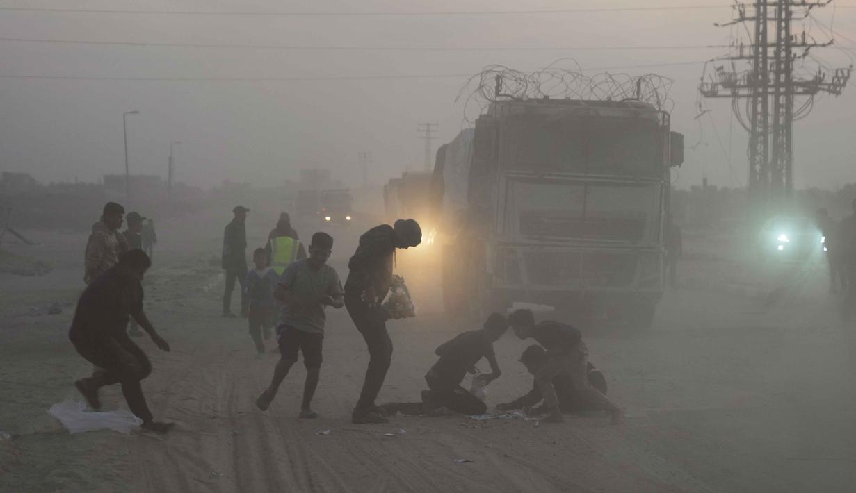 Menurut mekanisme 2720 PBB, mayoritas dari bantuan besar ini adalah bahan makanan. Tampak dalam foto, warga Palestina berbondong-bondong menuju truk yang mengangkut bantuan dari Program Pangan Dunia (WFP) saat truk-truk tersebut melintasi Deir al-Balah di Gaza Tengah, Sabtu, 8 November 2025. (AP Photo/Abdel Kareem Hana)