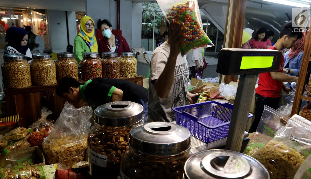Pedagang melayani pembeli kue kering di Pasar Mayestik, Jakarta Selatan, Senin (11/6). Separuh Ramadan dan jelang lebaran masyarakat mulai berburu kue kering. (Liputan6.com/Johan Tallo)