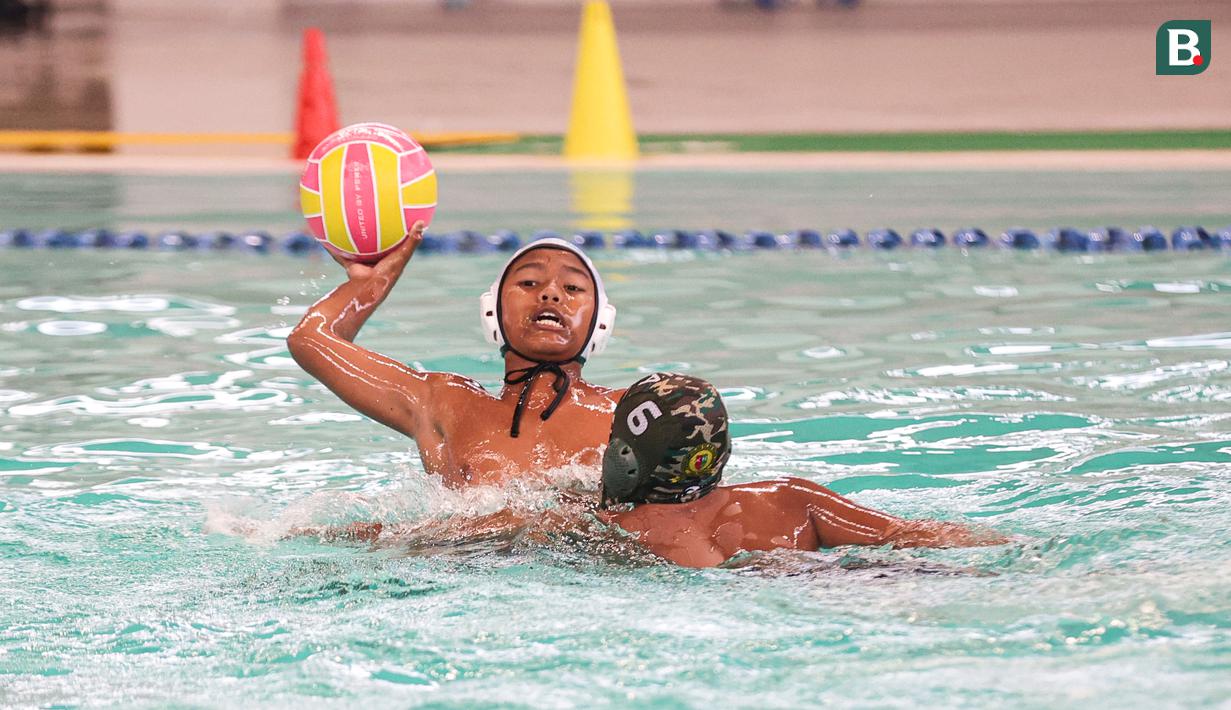 Pemain Pari Sakti (kiri) mencoba mempertahankan bola pada partai final polo air kategori U-14 Indonesia Open Aquatic Championships (IOAC) 2025 di Stadion Akuatik GBK, Jakarta Pusat, pada Kamis (13/11/2025). (Bola.com/Abdul Aziz)