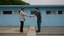 Dua pria berpose menirukan jabat tangan Presiden Korea Selatan Moon Jae In dengan Pemimpin Korea Utara Kim Jong Un di replika desa perbatasan DMZ Panmunjom di Namyangju, Sabtu (5/5). Replika Panmunjom menjadi wisata baru setelah KTT Korea. (AFP/Ed JONES)