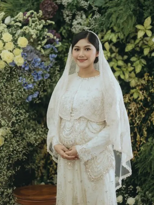 Saat tasyakuran baru-baru ini, Erina Gudono tampil dengan dress putih panjang yang dihiasi payetan dipadukan kerudung organza berpayet.  [@erinagudono]