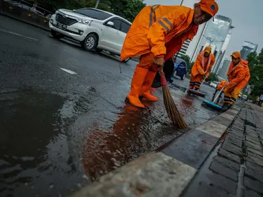 Petugas Dinas Kebersihan membersihkan genangan air usai hujan di kawasan jalan Sudirman, Jakarta, Rabu (22/11). Buruknya sistem drainase membuat petugas membersihkan genangan setiap kali hujan, meski dengan peralatan seadanya. (Liputan6.com/Faizal Fanani)