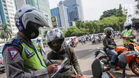 Petugas kepolisian lalu lintas saat menilang pengendara motor saat Operasi Zebra Jaya 2020 di kawasan Cawang, Jakarta, Senin (26/10/2020). Operasi Zebra Jaya dilaksanakan pada 26 Oktober-8 November 2020 untuk menekan jumlah pelanggaran lalu lintas. (Liputan6.com/Faizal Fanani)