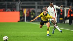 Penyerang AC Milan, Rafael Leao (kiri) berebut bola dengan bek Borussia Dortmund, Nico Schlotterbeck, pada matchday 2 Grup F Liga Champions 2023/2024 di Signal Iduna Park, Kamis (5/10/2023) WIB. (INA FASSBENDER / AFP)