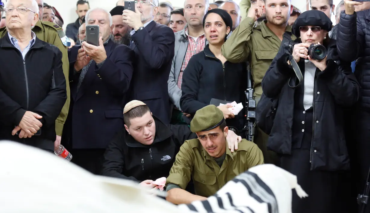 Tentara Israel dan kerabat Yosef Cohen menangis saat pemakamannya di Yerusalem, Jumat (14/12). Penembakan terhadap dua tentara Israel terjadi beberapa jam setelah pasukan Israel menembak mati dua warga Palestina di Tepi Barat. (AP Photo/Ariel Schalit)