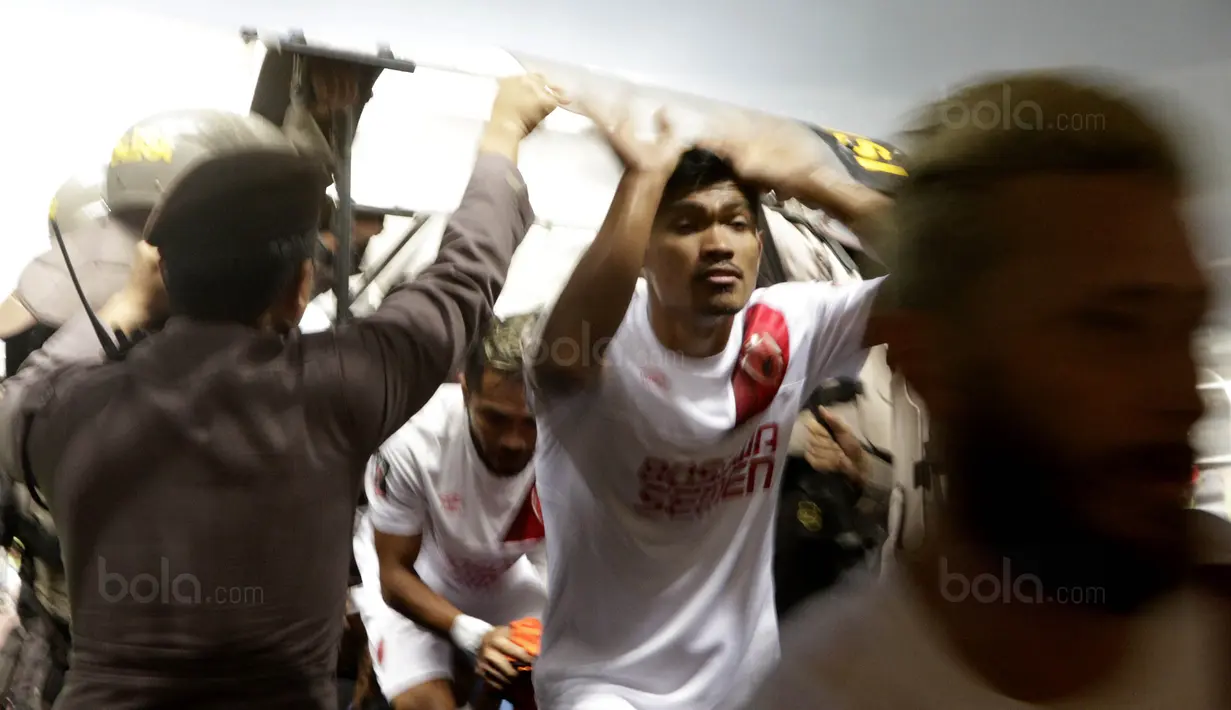 Petugas kepolisian melindungi pemain PSM dari lemparan botol usai pertandingan melawan Persib pada laga Piala Presiden di Stadion GBLA, Bandung, Jumat (26/1/2018). Persib takluk 0-1 dari PSM. (Bola.com/M Iqbal Ichsan)