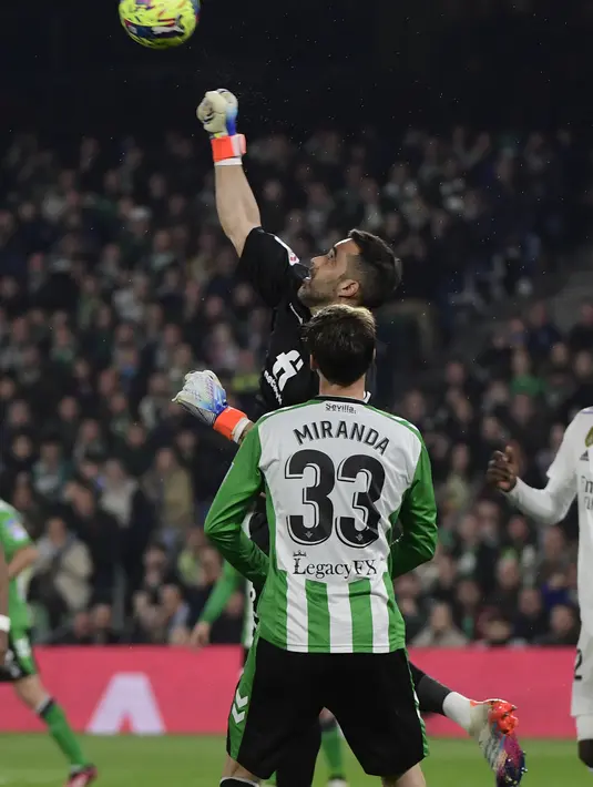 Kiper Real Betis, Claudio Bravo (atas) membelokkan saat bertanding melawan Real Madrid pada pertandingan La Liga Spanyol di stadion Benito Villamarin di Seville, Senin(6/3/2023). Tim besutan Carlo Ancelotti tertinggal 9 angka dari Barcelona di puncak klasemen. (AFP/CRISTINA QUICLER)