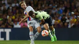 Gelandang Barcelona Frenkie de Jong berebut bola dengan penyerang Manchester City Julian Alvarez pada sebuah laga amal di Stadion Camp Nou, Kamis (25/8/2022) dini hari WIB. Laga Barcelona vs Man City berjalan ketat, skor akhir sama kuat 3-3. (AP Photo/Joan Monfort)