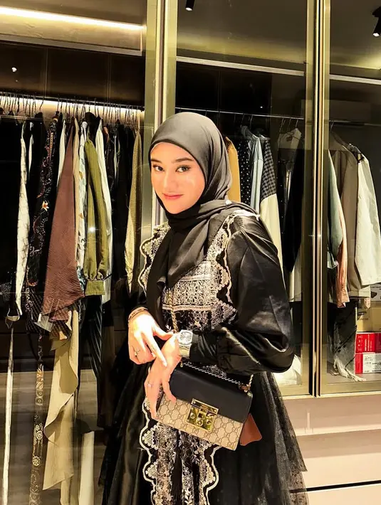 Kerudung hitam juga dipadukan dress ruffle lace hitam berbordir putih. Ia membawa sling bag rantai dari Gucci. [@clarashintareal]