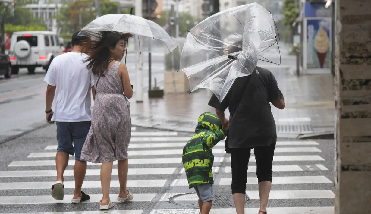 <p>Orang-orang menyusuri jalan tempat wisata yang terkenal "Kokusai-dori" saat badai tropis mendekat di Naha, Pulau Okinawa, Jepang, Kamis (1/6/2023). (AP Photo/Hiro Komae)</p>