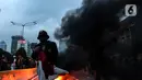 Massa aksi demo menolak Omnibus Law UU Cipta Kerja membakar ban bekas di Jalan Medan Merdeka Barat, Jakarta Pusat, Selasa (20/10/2020). Gelombang protes tolak UU Cipta Kerja belum surut sejak disahkan pada 5 Oktober lalu. (Liputan6.com/Johan Tallo)