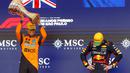 Pembalap Red Bull Racing, Max Verstappen (kanan) tertunduk saat pembalap McLaren, Lando Norrris mengangkat trofi kemenangan dalam Formula 1 GP Sao Paulo di Interlagos, Sao Paulo, Brasil, Minggu (09/11/2025). (AFP/Miguel Schincariol)