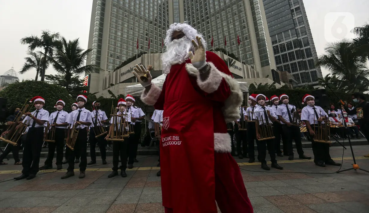 Seorang berpakaian sinterklas berdiri di depan peserta yang sedang bermain angklung saat acara Christmas in Jakarta di Bundaran Hotel Indonesia, Jakarta, Selasa (21/12/2021). Pemerintah Provinsi DKI Jakarta menggelar Christmas in Jakarta dalam rangka menyambut Natal 2021. (Liputan6.com/Johan Tallo)