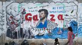 Anak-anak Palestina melihat mural yang menggambarkan pencegatan kapal-kapal yang berpartisipasi dalam Armada Sumud Global, sebuah misi bantuan kemanusiaan yang dipimpin sipil ke Gaza melalui laut, di Nuseirat, Jalur Gaza Tengah pada 19 Mei 2026. (Eyad Baba/AFP)