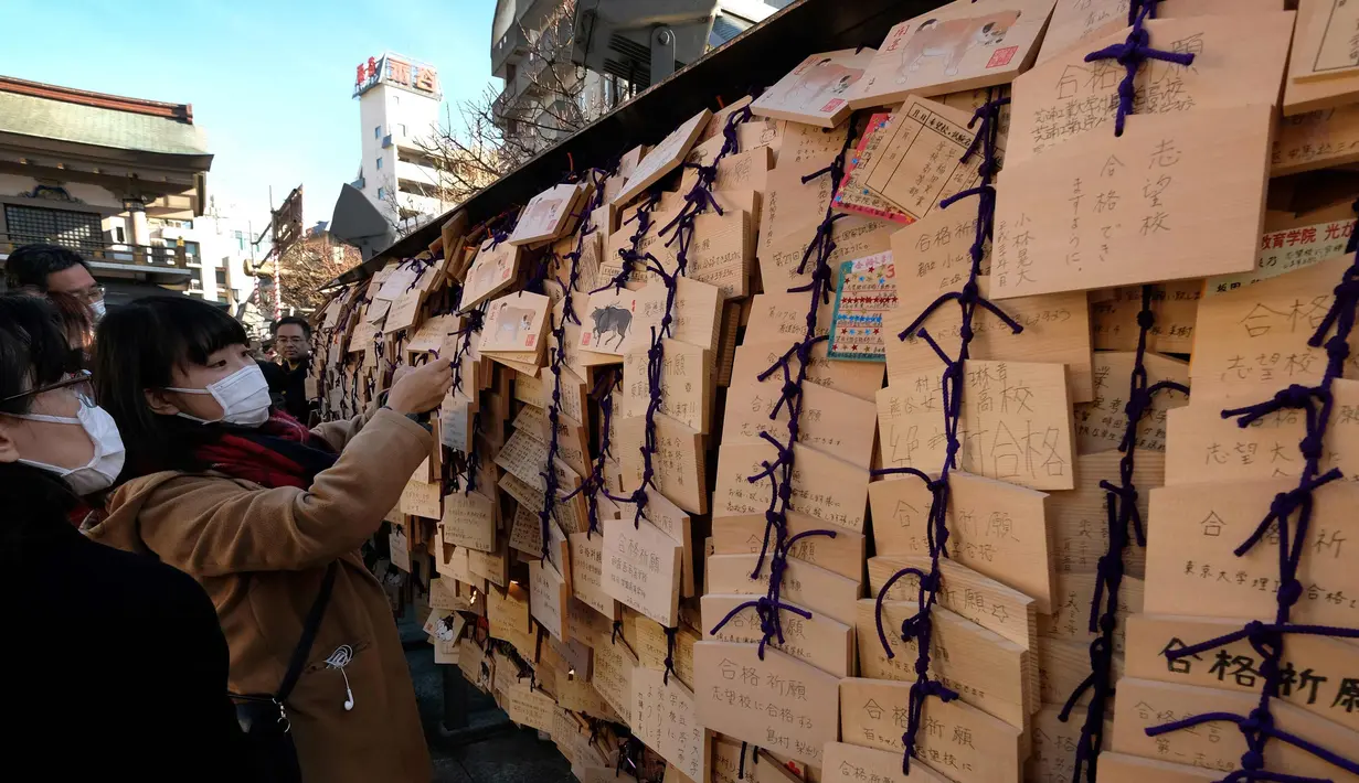 Para pelajar menaruh papan Ema berisi harapan mereka di Kuil Yushima Tenmangu, Tokyo, Jepang, (7/1). Para siswa dan orang tua di Tokyo ramai-ramai mengunjungi Kuil Yushima Tenmangu untuk berdoa sebelum ujian sekolah dimulai. (AFP Photo/Kazuhiro Nogi)