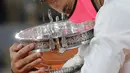 Petenis Rafael Nadal memegang trofi saat merayakan kemenangannya atas Novak Djokovic pada final Prancis Terbuka 2020 di Stadion Roland Garros, Paris, Prancis, Minggu (11/10/2020). Dengan kemenangan ini, Nadal menyamai rekor Roger Federer dengan meraih 20 gelar Grand Slam. (AP Photo/Christophe Ena)