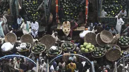 Orang-orang berdagang semangka di pasar buah di Lahore, Pakistan (12/4/2022).  Semangka biasa dipanen buahnya untuk dimakan segar atau dibuat jus. (AFP/Arif Ali)