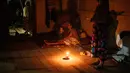 Hingga Selasa 16 Desember 2025 malam, warga yang mengungsi akibat banjir bandang pada akhir November 2025 bertahan hidup dalam kegelapan malam tanpa penerangan lampu listrik. Tampak dalam foto, Nurlimah (C), 65 tahun, yang tidak dapat berjalan sejak mengalami cedera dalam kecelakaan tabrak lari setahun lalu, duduk sambil berlindung di rumah tetangga yang sebagian runtuh di sebelah rumahnya, yang hanyut tersapu banjir bandang di Aceh Tamiang, pada Selasa 16 Desember 2025. (Yasuyoshi Chiba/AFP)