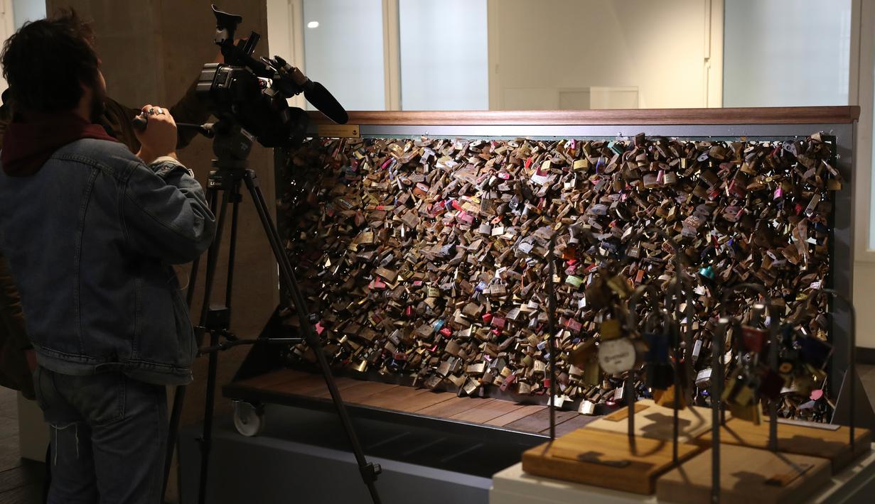 Awak media mengambil gambar gembok cinta dari Jembatan Pont des Art saat dilelang oleh Ville de Paris, Prancis, Rabu (3/5). Penjualan dari lelang itu diharapkan akan mengumpulkan uang hingga 107.250 dolar untuk pengungsi di Paris. (Jacques DEMARTHON/AFP)