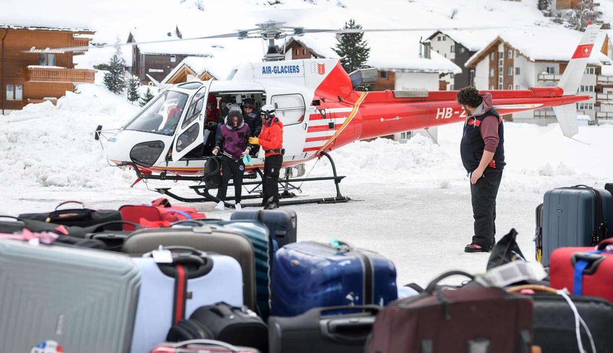 Sejumlah turis turun dari helikopter setelah dievakuasi dari resor ski Zermatt di  Taesch, Pegunungan Alpen Swiss (10/1). Sekitar 13.000 wisatawan terjebak akibat bencana tersebut. (AFP Photo/Fabrice Coffrini)