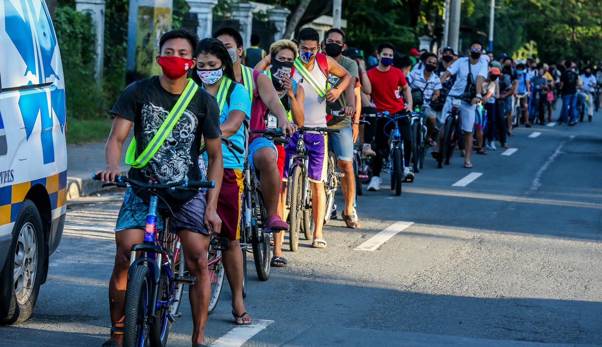 Para pengendara sepeda mengantre untuk mendapatkan helm dan selempang reflektif gratis yang dibagikan oleh sejumlah anggota lembaga swadaya masyarakat di Manila, Filipina (9/7/2020). (Xinhua/Rouelle Umali)