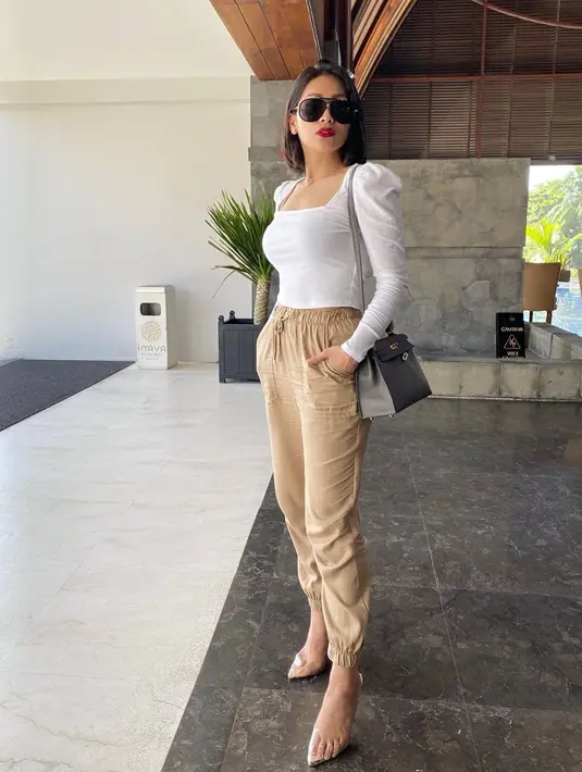 Gaya OOTD Tata Janeeta dengan busana putih serta celana cokelat ini pun membuatnya terlihat menawan. Ia juga memilih memadukan penampilannya dengan sling bag serta sepatu transparan yang cukup unik. (Liputan6.com/IG/@tatajaneetaofficial)
