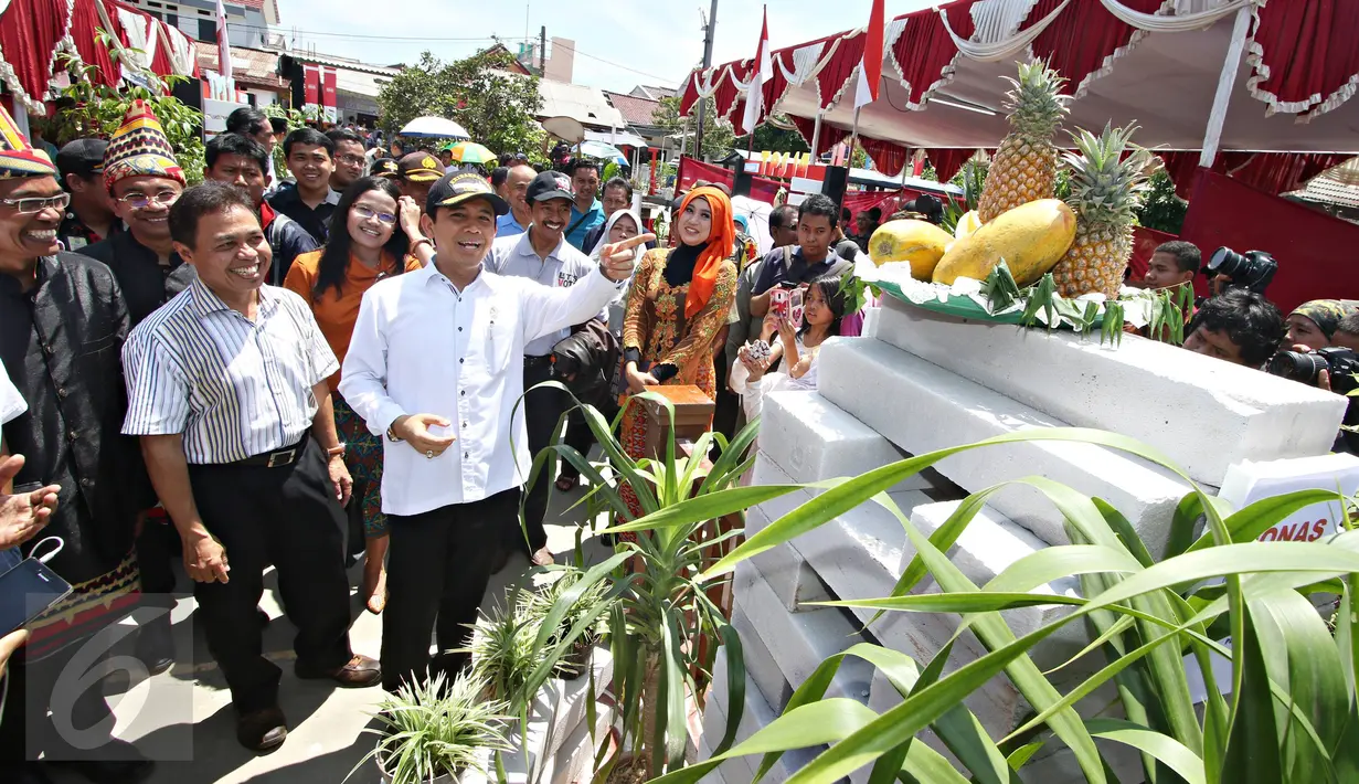 Menpan RB Yuddy Chrisnandi (topi) menunjuk sebuah monumen yang dibuat oleh para panitia TPS Kampung Pilkada RW 03 di Depok, Jawa Barat, Rabu (9/12). Menpan hadir ke TPS untuk melakukan pemantauan Pemilihan Umum yang aman.  (Liputan6.com/Immanuel Antonius)