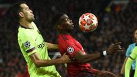 Gelandang Barcelona, Sergio Busquets berebut bola dengan gelandang Manchester United, Paul Pogba pada leg pertama perempat final Liga Champions di Stadion Old Trafford, Rabu (10/4). Barcelona menang tipis 1-0 atas Manchester United. (Oli SCARFF / AFP)