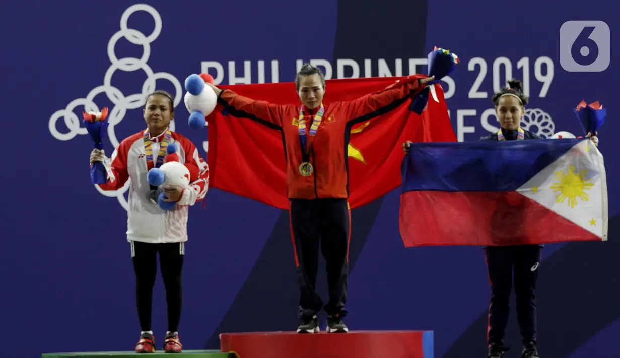Lifter putri Indonesia, Lisa Setiawati (kiri) saat naik podium usai mendapatkan medali perak SEA Games 2019 cabang angkat besi nomor 45 kg di Stadion Rizal Memorial, Manila, Minggu (1/12/2019). Dirinya meraih perak dengan total angkatan 169 kg. (Bola.com/M Iqbal Ichsan)