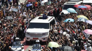 Presiden Republik Indonesia periode 2024-2029, Prabowo Subianto (tengah) melambaikan tangan kepada para pendukungnya saat menuju Istana Kepresidenan usai prosesi pelantikan di Jakarta pada Minggu 20 Oktober 2024. (Aditya Aji/AFP)