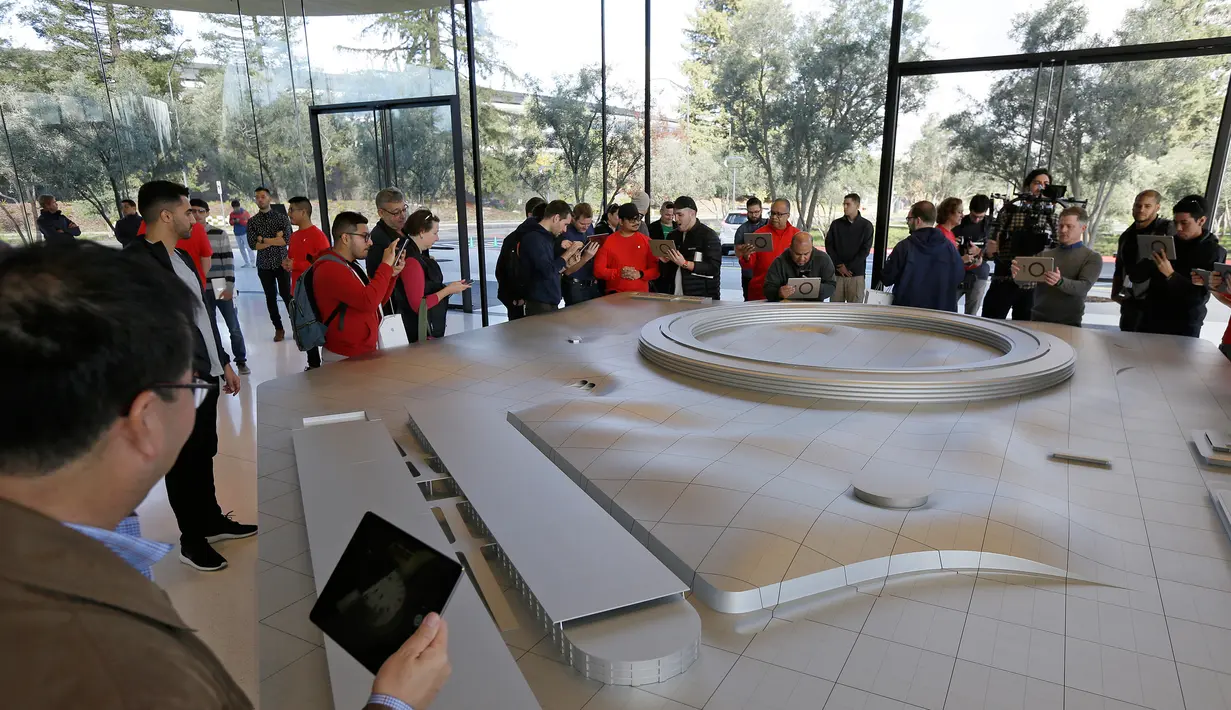 Pengunjung menggunakan iPad saat melihat Augmented Reality (AR) di area khusus Visitor Center kawasan Apple Park di Cupertino, California, Jumat (17/11). Mereka bisa melihat salah satu panel surya terbesar di dunia hadir di Apple Park (AP/Eric Risberg)