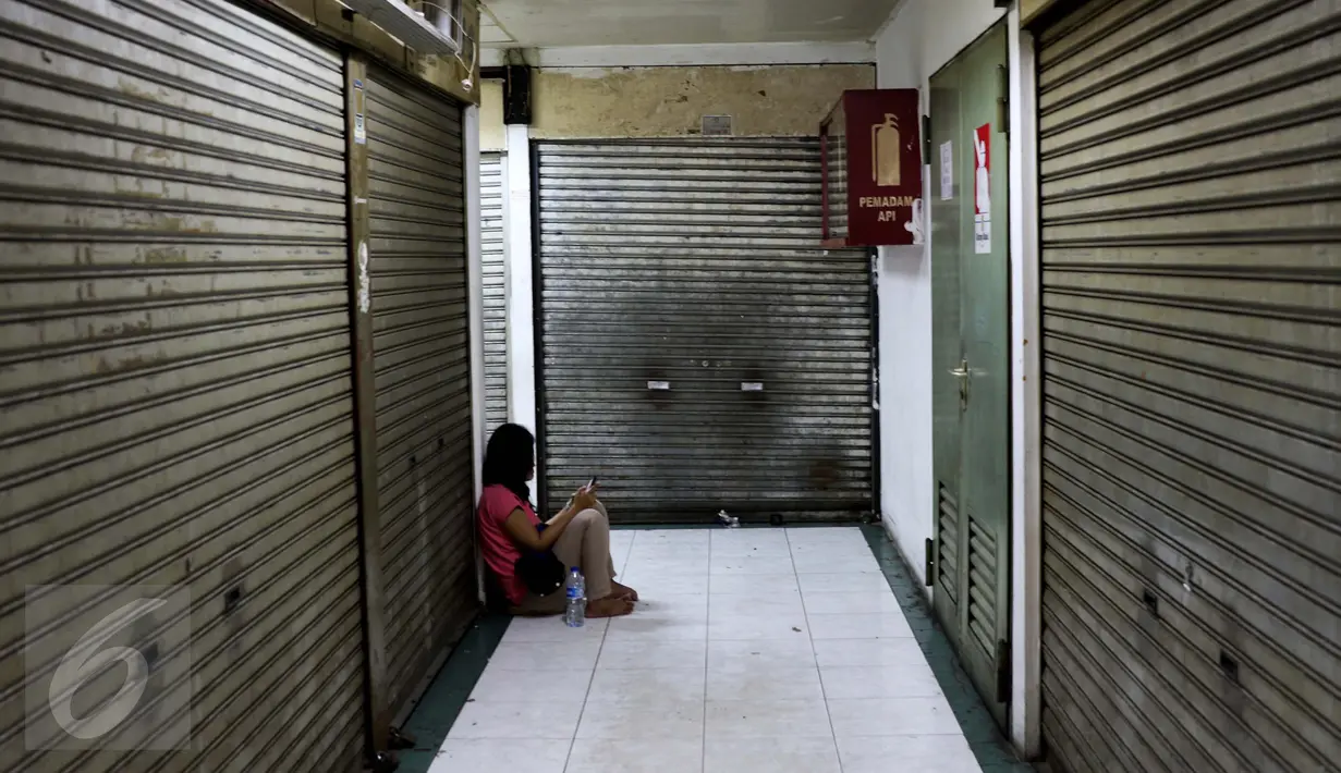 Seorang wanita duduk di antara ruko yang tutup di kawasan Glodok, Jakarta Barat, Jumat (4/11). Khawatir jadi sasaran anarkisme para pendemo, pedagang di kawasan Glodok memilih libur dan menutup toko. (Liputan6.com/Gempur M Surya)