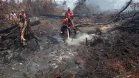 Petugas pemadam kebakaran lahan di Rupat menyiram bara api di gambut agar tak berkobar lagi diterpa angin. (Liputan6.com/M Syukur)