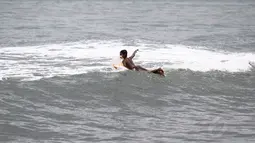  Dengan bertelanjang dada, anak nelayan ini menuju ke tengah laut mencari titik ombak yang siap melesatkan papan selancarnya (Liputan6.com/Faizal Fanani)