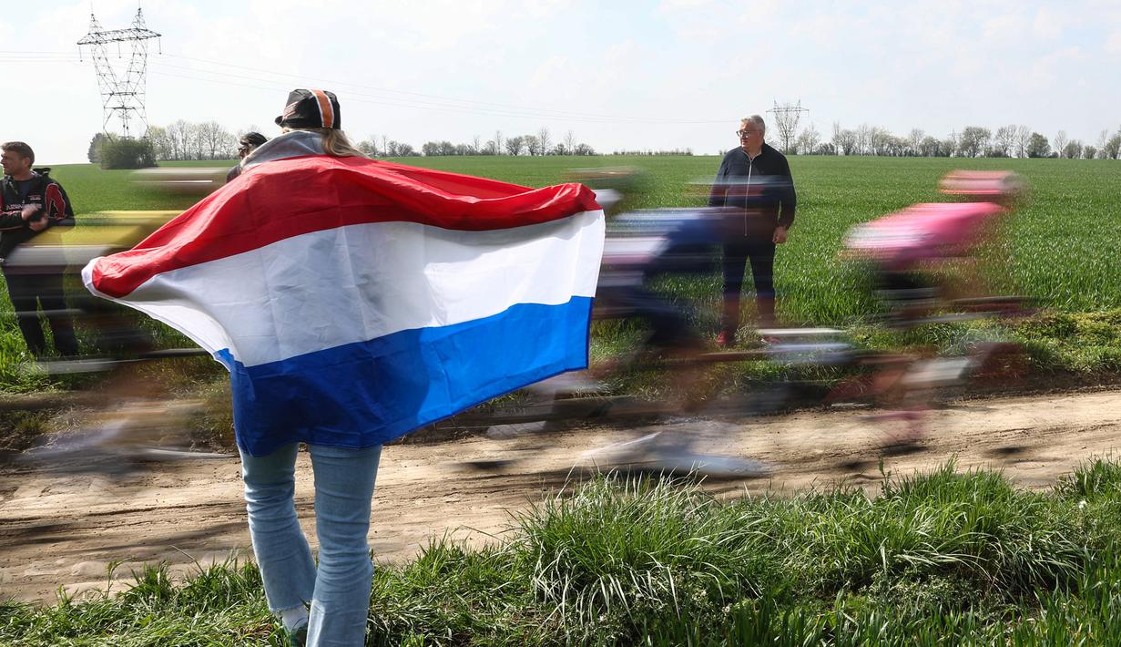 Penonton memegang bendera Belanda saat ajang balap sepeda Paris Roubaix 2023 yang menempuh Compiegne hingga Roubaix, Prancis utara, 9 April 2023. (AFP/Anne-Christine Poujoulat)