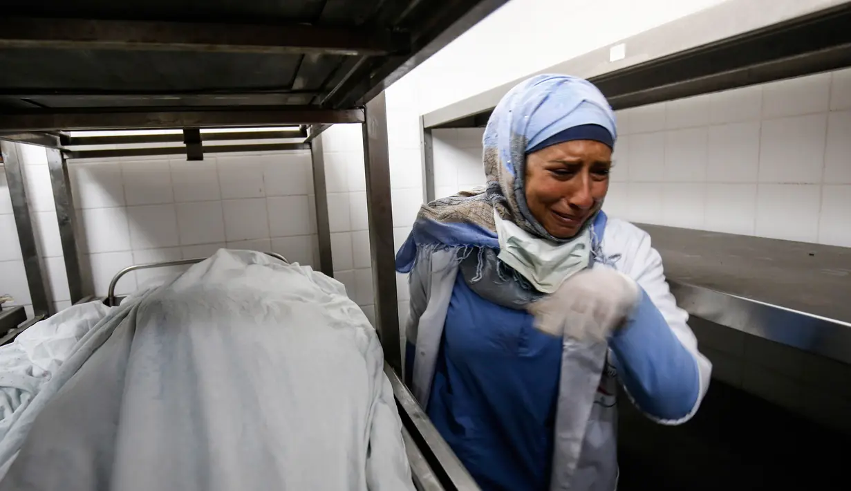Seorang perawat menangis atas kematian rekannya Razan al-Najjar di kamar jenazah di rumah sakit Khan Yunis di Jalur Gaza selatan (1/6). Razan tewas ditembak oleh tentara Israel di dekat pagar perbatasan Gaza. (AFP Photo/Kata Khatib)