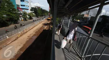 Penumpang bus transjakarta berjalan di samping pembangunan proyek underpass Matraman di Jakarta, Rabu (5/4). Proyek senilai Rp118 miliar itu ditargetkan selesai pada akhir 2017. (Liputan6.com/Immanuel Antonius)