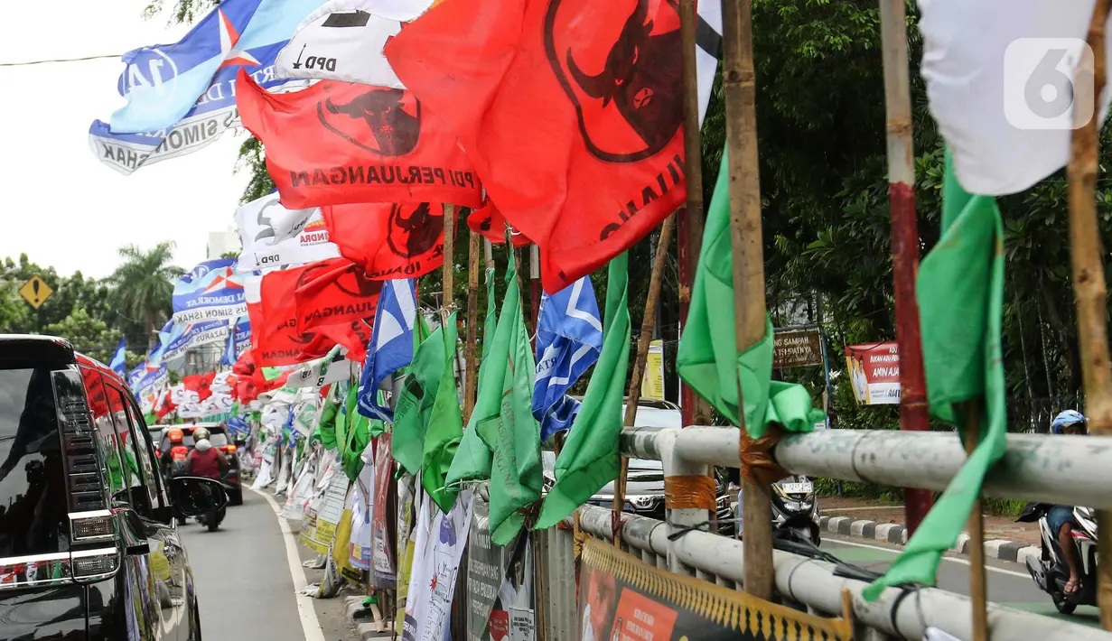 Pemasangan bendera partai politik di pagar pembatas sangat membahayakan keselamatan pengguna jalan. (Liputan6.com/Herman Zakharia)