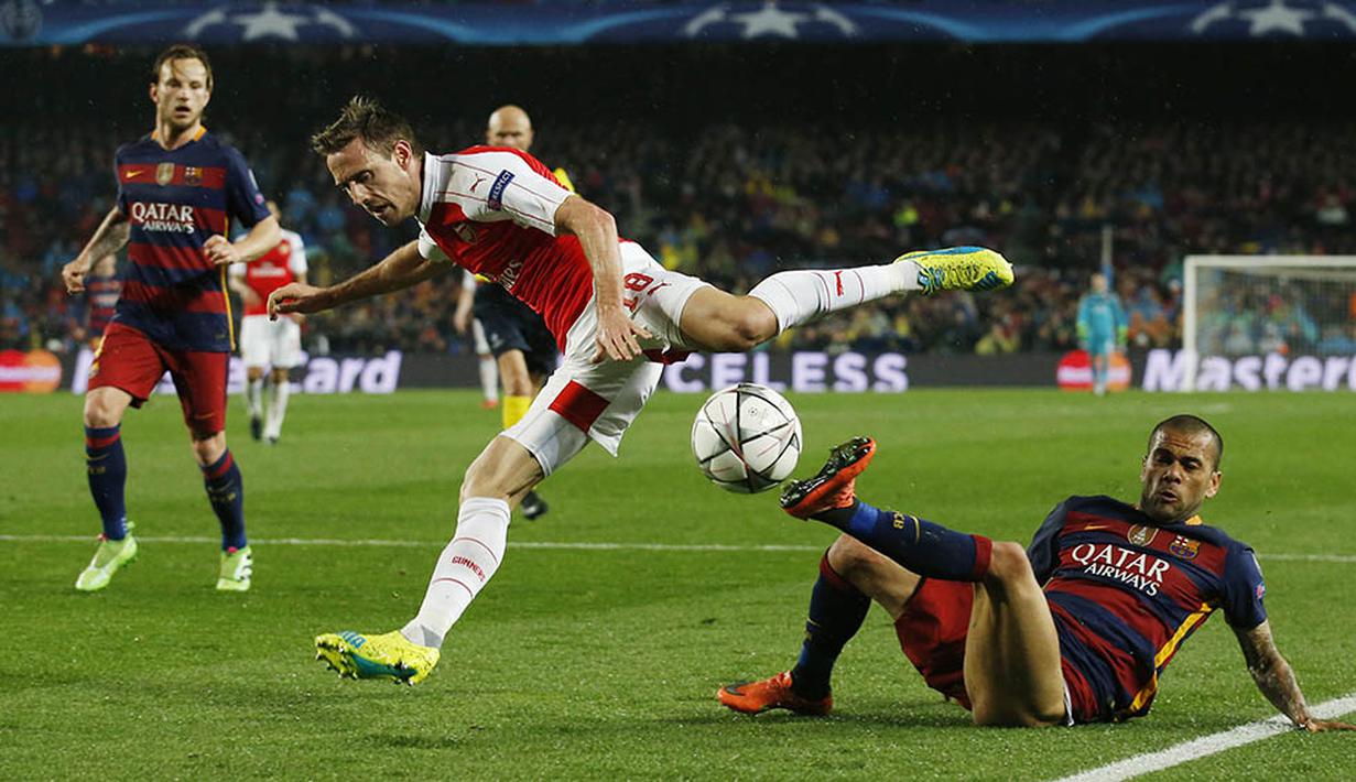 Bek sayap Barcelona, Dani Alves, melakukan tekel kepada bek sayap Arsenal, Nacho Monreal, pada laga leg kedua babak 16 besar Liga Champions di Stadion Camp Nou, Kamis (16/3/2016) dini hari WIB. (Reuters/Albert Gea)