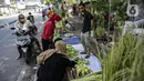 Pedagang cangkang ketupat melayani pembeli di kawasan Palmerah, Jakarta, Minggu (18/7/2021). Sepinya pembeli membuat para pedagang menjual cangkang ketupat hanya dengan harga Rp 5 ribu per ikat, padahal biasanya Rp 8 ribu per ikat. (Liputan6.com/Faizal Fanani)