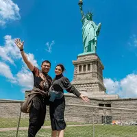 Anang Hermansyah saat berpose bersama istrinya Ashanty berpose di bawah Patung Liberty. Keduanya kompak mengenakan outfit serba hitam. (Instagram/ashanty_ash)