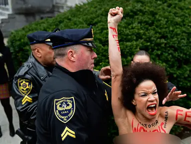 Pengunjuk rasa wanita mendatangi sidang kekerasan seksual komedian Bill Cosby di Gedung Pengadilan Montgomery, Pennsylvania, Amerika Serikat, Senin (9/4). Wanita itu ditahan karena tampil topless. (AP Photo/Corey Perrine)